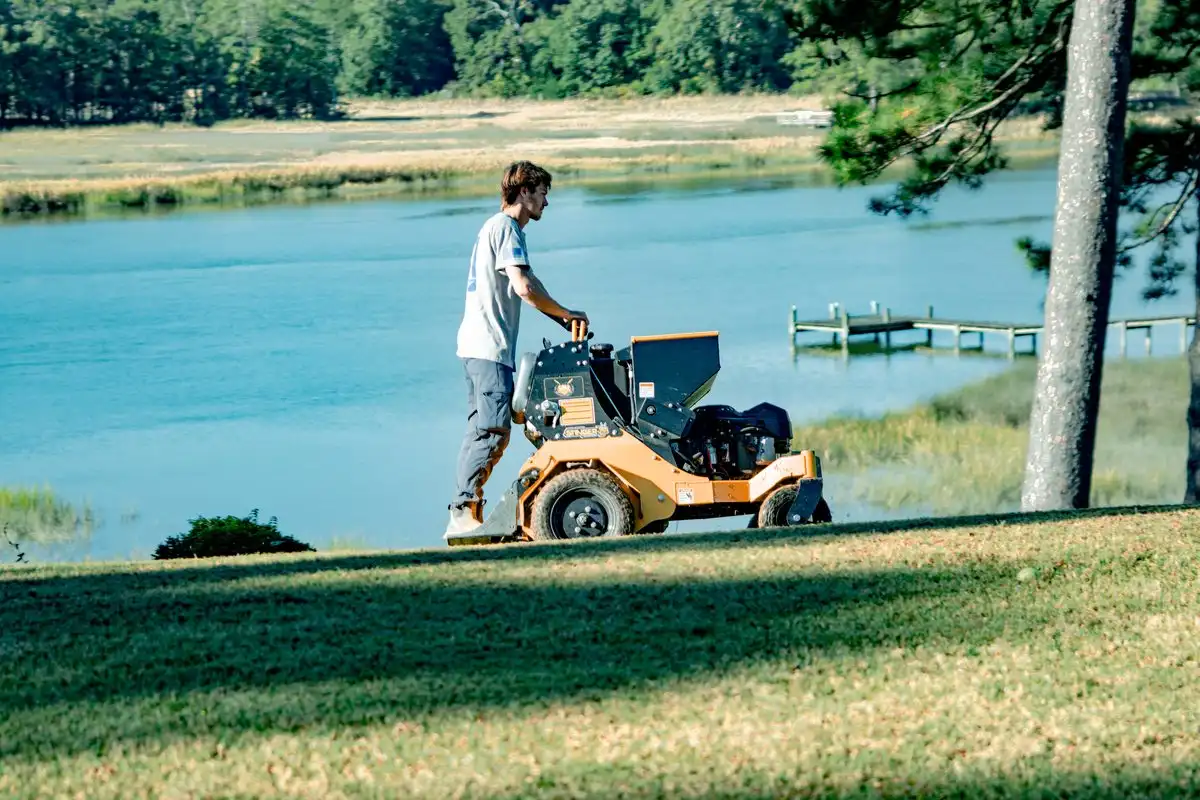 A Meadow Lawn and Pest technician feeding a lush lawn beside the water in Hampton Roads